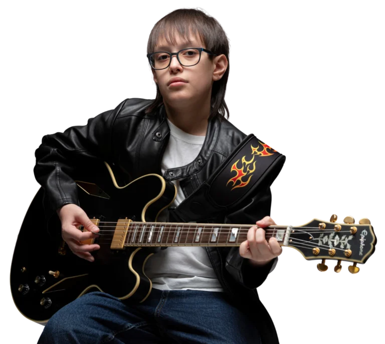 Holden Garcia wearing glasses and a black jacket, seated with a black acoustic guitar.