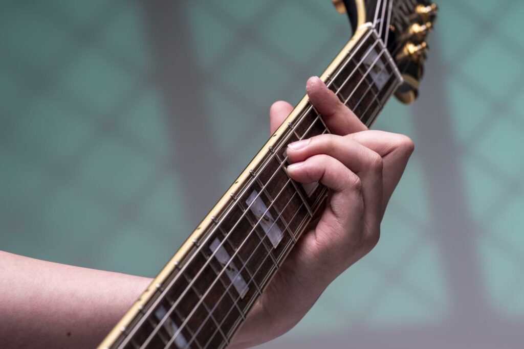 Close-up of a hand forming a chord on an acoustic guitar.