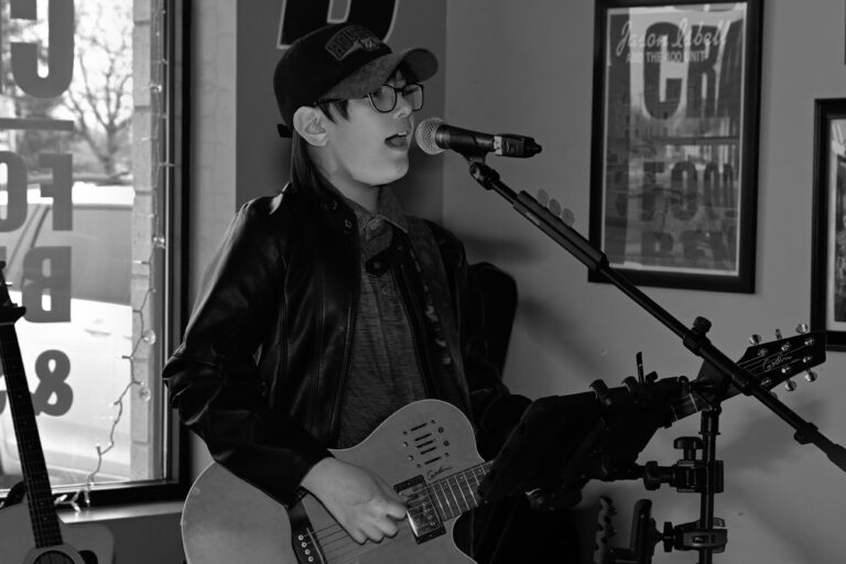 Black-and-white photograph of Holden Garcia singing and playing acoustic guitar.
